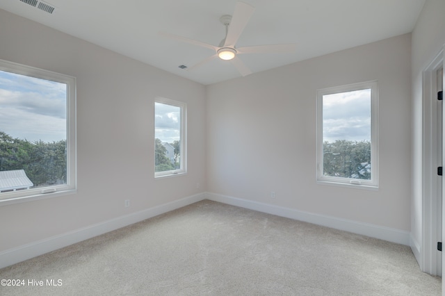 spare room with light colored carpet, ceiling fan, and plenty of natural light