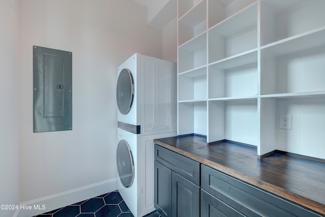 laundry area with stacked washer / dryer, electric panel, cabinets, and dark hardwood / wood-style floors