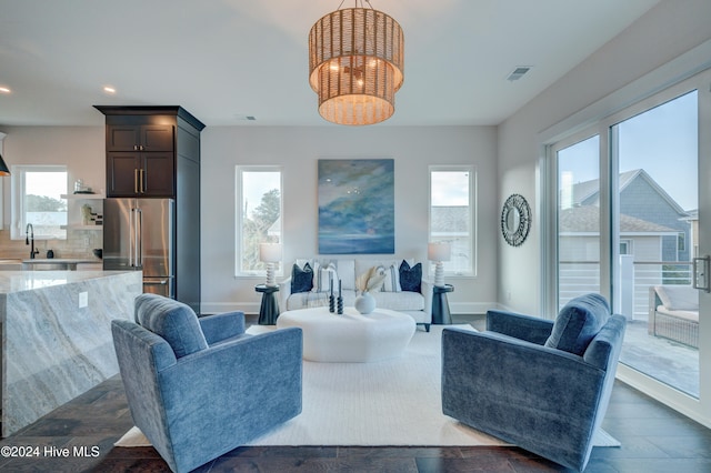 living room with dark wood-type flooring, a chandelier, and sink