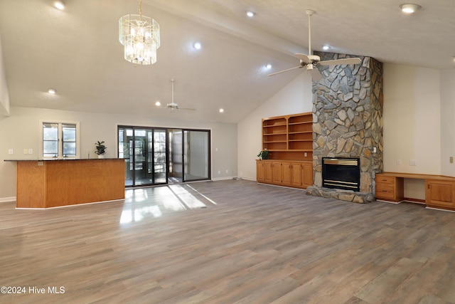 unfurnished living room with hardwood / wood-style floors, ceiling fan with notable chandelier, a fireplace, and high vaulted ceiling