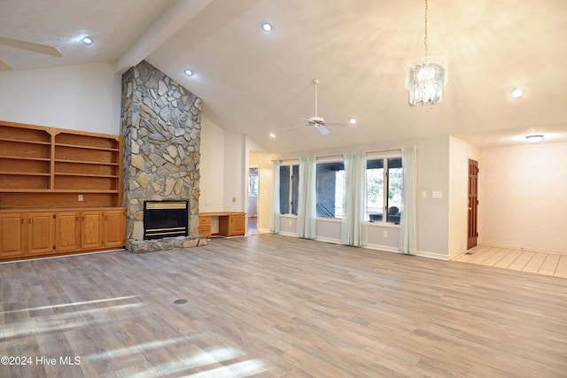 unfurnished living room featuring high vaulted ceiling, ceiling fan with notable chandelier, light hardwood / wood-style floors, a fireplace, and beam ceiling