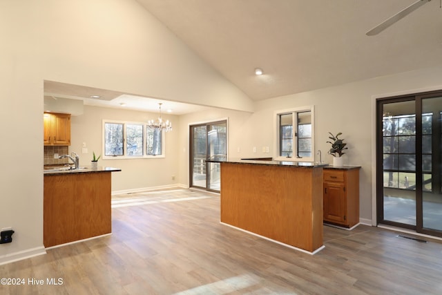 kitchen featuring high vaulted ceiling, hanging light fixtures, dark stone countertops, wood-type flooring, and a chandelier