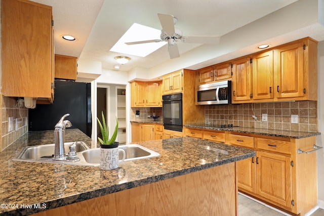 kitchen with kitchen peninsula, a skylight, tasteful backsplash, sink, and black appliances