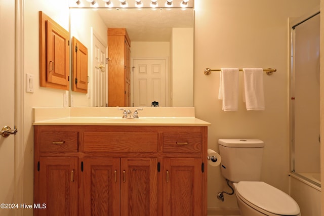 full bathroom featuring vanity, toilet, and shower / bath combination with glass door