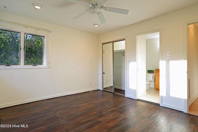 unfurnished bedroom with a closet, dark hardwood / wood-style floors, ensuite bath, and ceiling fan