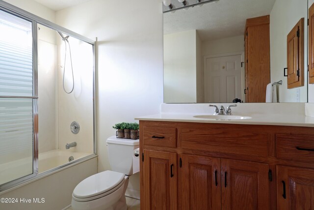 full bathroom featuring tile patterned floors, vanity, toilet, and bath / shower combo with glass door