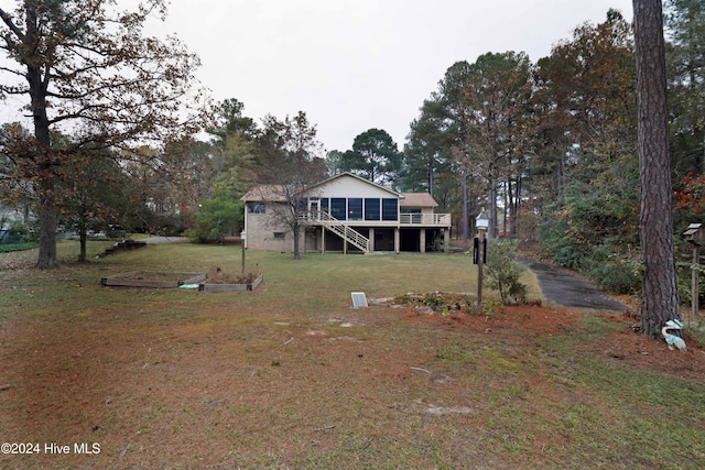 rear view of property with a yard, a deck, and a sunroom