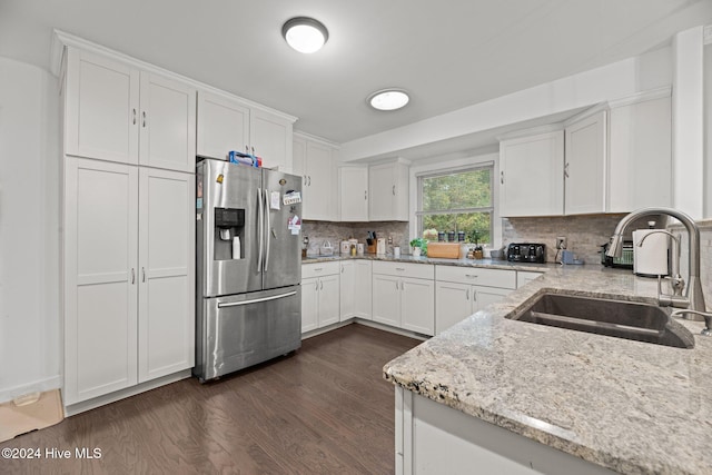 kitchen with sink, light stone counters, white cabinets, stainless steel fridge, and dark hardwood / wood-style flooring