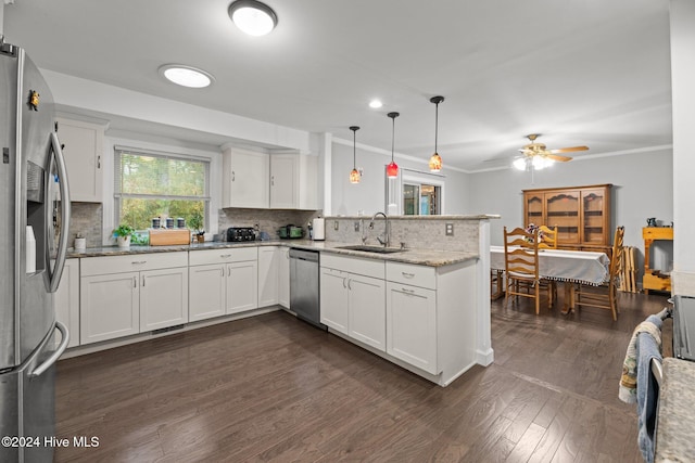 kitchen featuring sink, kitchen peninsula, appliances with stainless steel finishes, white cabinets, and pendant lighting