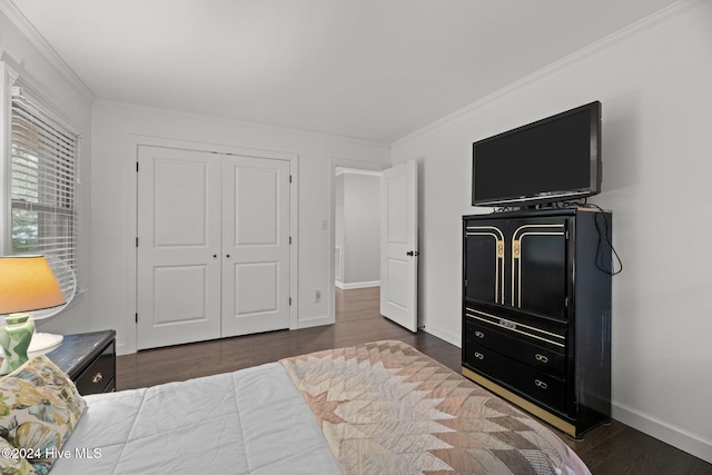 bedroom featuring dark wood-type flooring, a closet, and crown molding