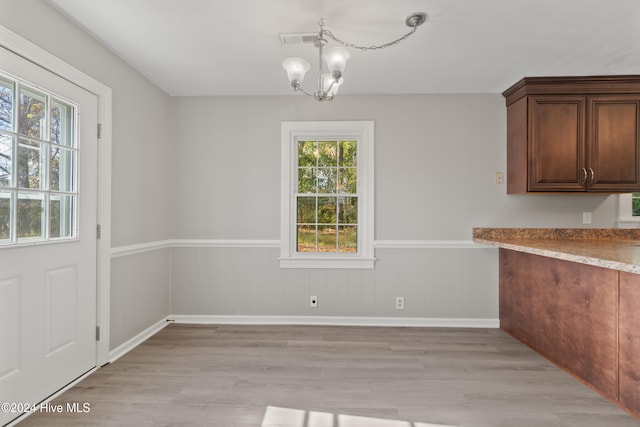 unfurnished dining area featuring a notable chandelier and light wood-type flooring