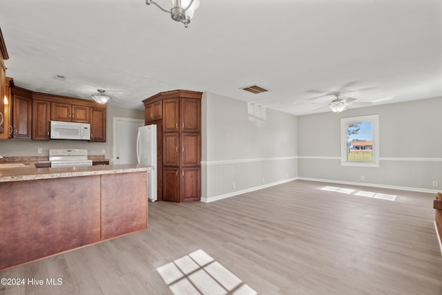 kitchen featuring sink, light wood-type flooring, ceiling fan, light stone countertops, and white appliances