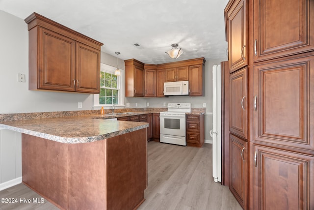 kitchen featuring decorative light fixtures, sink, light hardwood / wood-style floors, kitchen peninsula, and white appliances