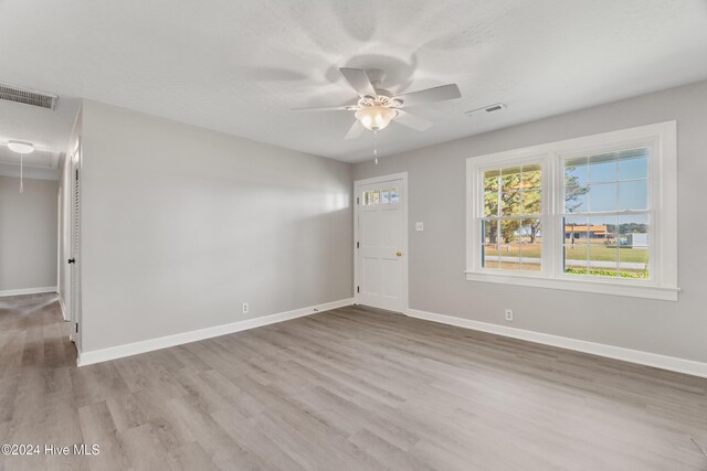 empty room featuring a textured ceiling, light hardwood / wood-style flooring, and ceiling fan