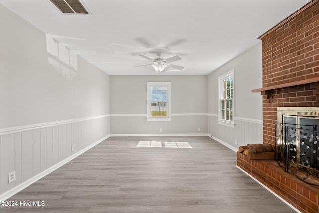 unfurnished living room with a brick fireplace, ceiling fan, and light hardwood / wood-style flooring