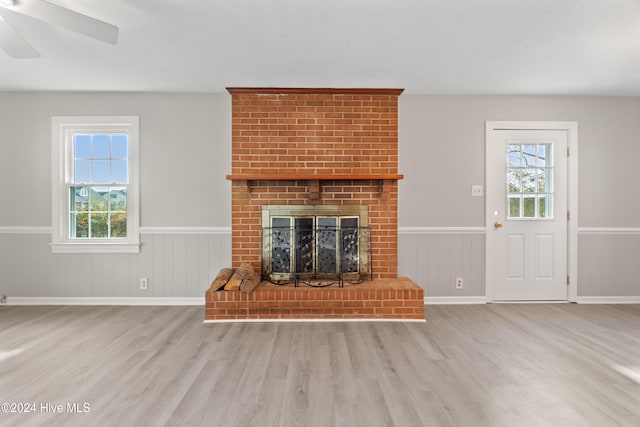 unfurnished living room featuring a brick fireplace, a wealth of natural light, light hardwood / wood-style floors, and ceiling fan