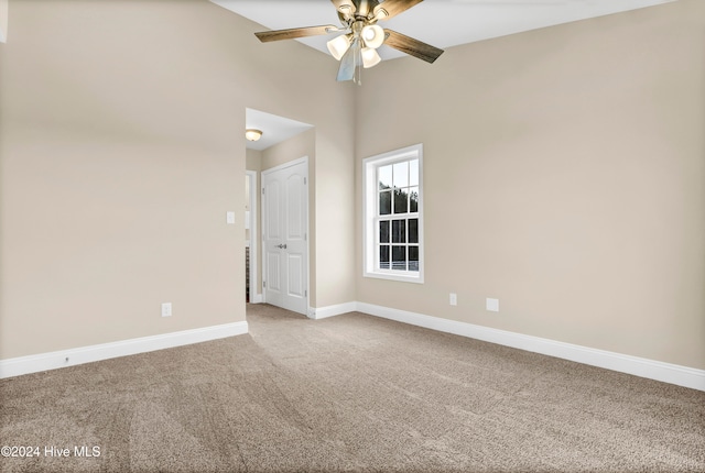 empty room featuring carpet, ceiling fan, and a high ceiling