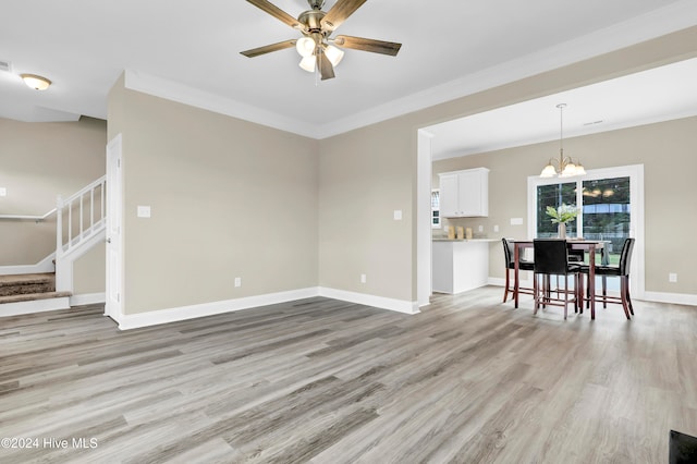 unfurnished living room featuring ceiling fan with notable chandelier, light hardwood / wood-style flooring, and crown molding