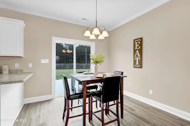 dining area with a notable chandelier, ornamental molding, and light hardwood / wood-style flooring