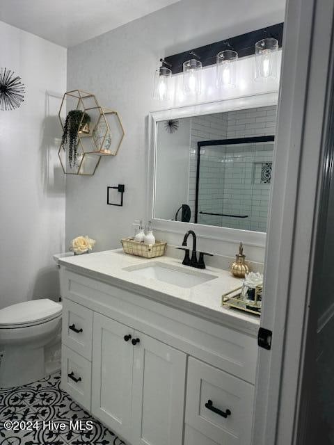 bathroom with tile patterned flooring, vanity, toilet, and walk in shower