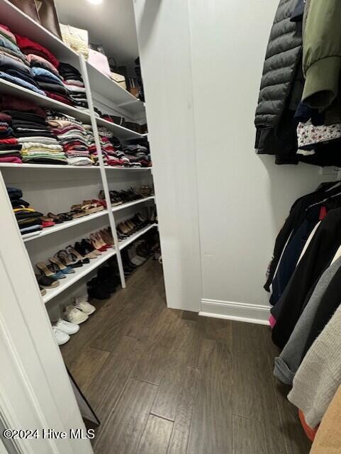 walk in closet with dark hardwood / wood-style floors