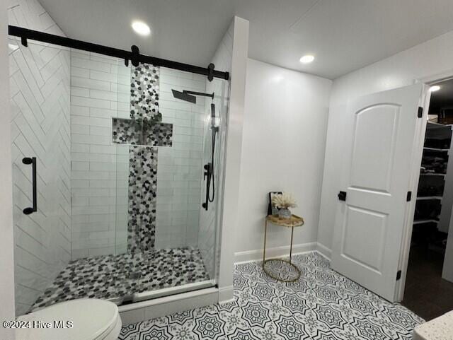 bathroom with tile patterned flooring, toilet, and a shower with door