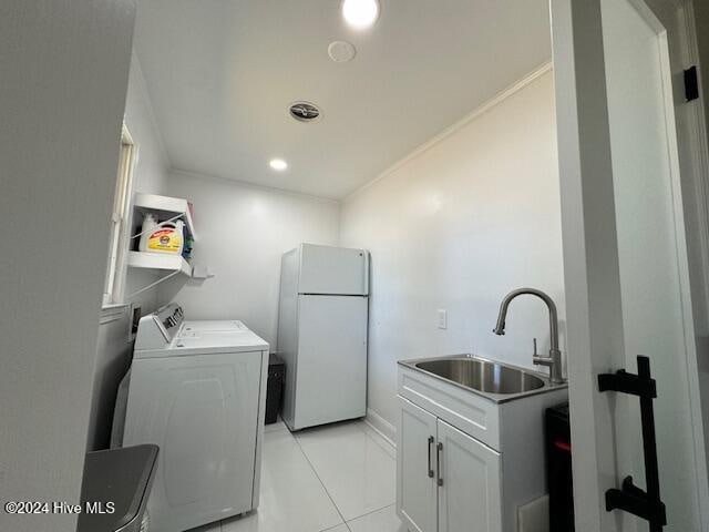 clothes washing area featuring sink, cabinets, washing machine and dryer, crown molding, and light tile patterned floors