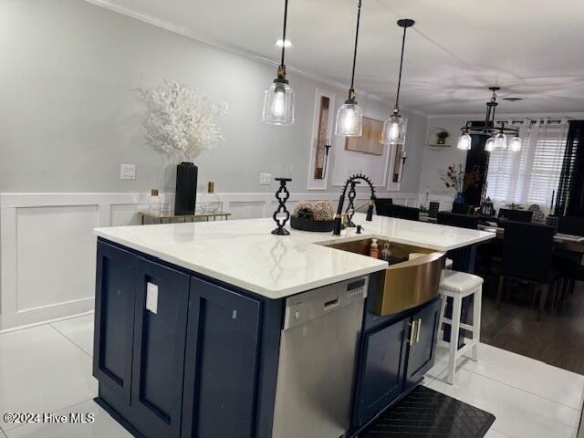 kitchen with pendant lighting, dishwasher, sink, blue cabinetry, and an island with sink