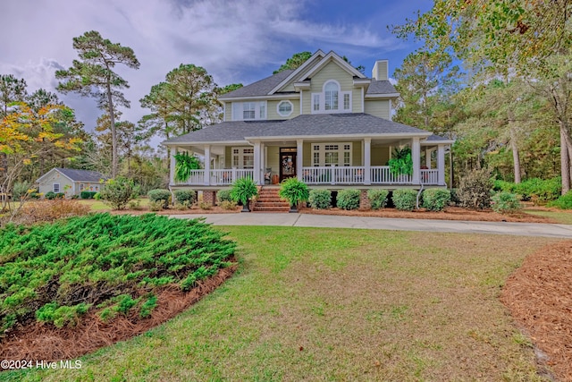 view of front of home featuring a porch, a front yard, roof with shingles, and a chimney