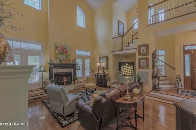 living area with stairway, wood finished floors, a high end fireplace, and a healthy amount of sunlight