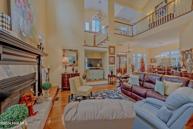 living area with plenty of natural light, a tiled fireplace, a chandelier, and wood finished floors