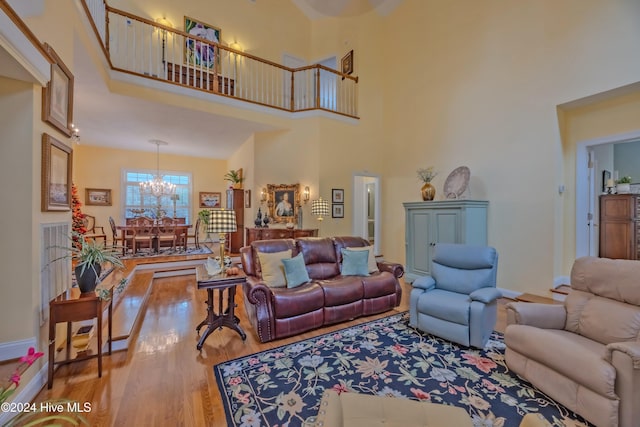 living room with a chandelier, a high ceiling, and wood finished floors