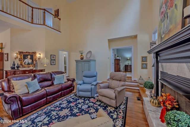 living room featuring a towering ceiling, a fireplace, wood finished floors, and visible vents