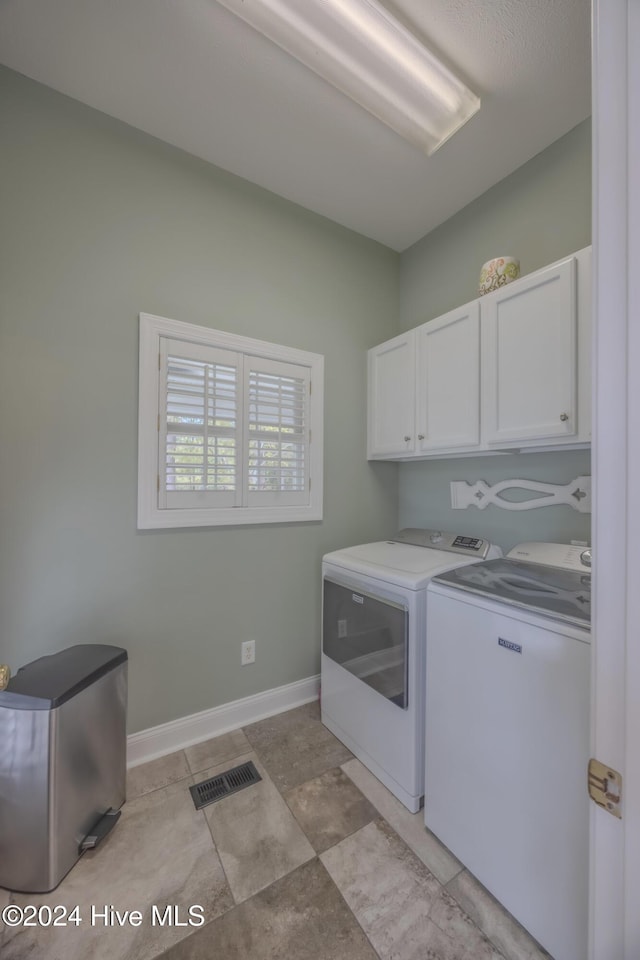 washroom featuring visible vents, separate washer and dryer, cabinet space, and baseboards