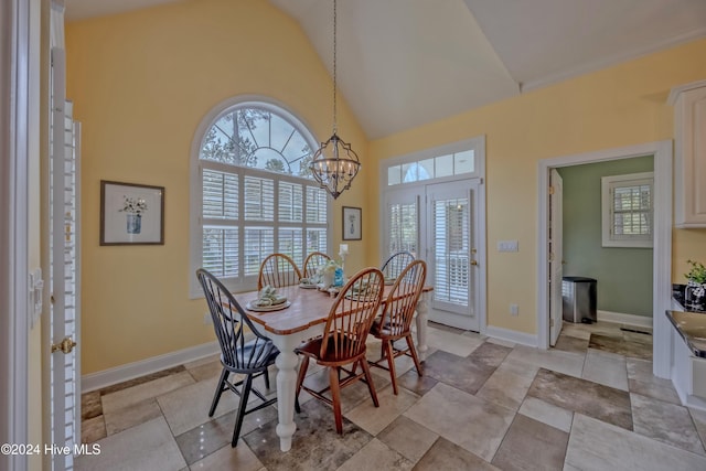 dining space with baseboards, high vaulted ceiling, and a notable chandelier