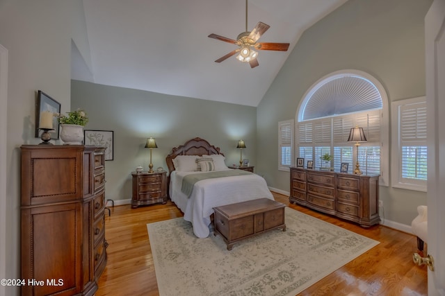 bedroom with light wood-style floors, high vaulted ceiling, and baseboards