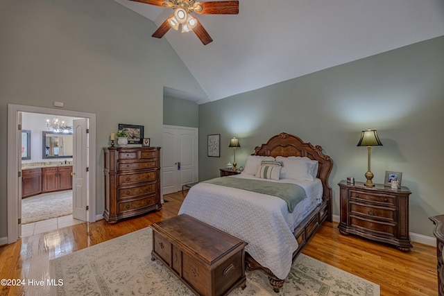 bedroom with baseboards, connected bathroom, light wood-type flooring, high vaulted ceiling, and ceiling fan with notable chandelier