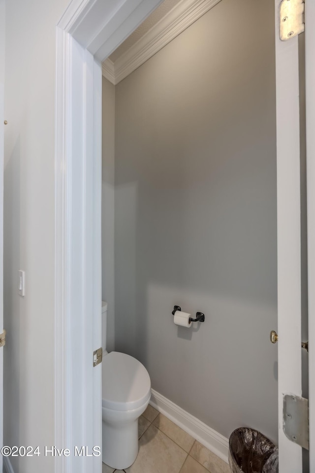 bathroom featuring baseboards, crown molding, toilet, and tile patterned floors