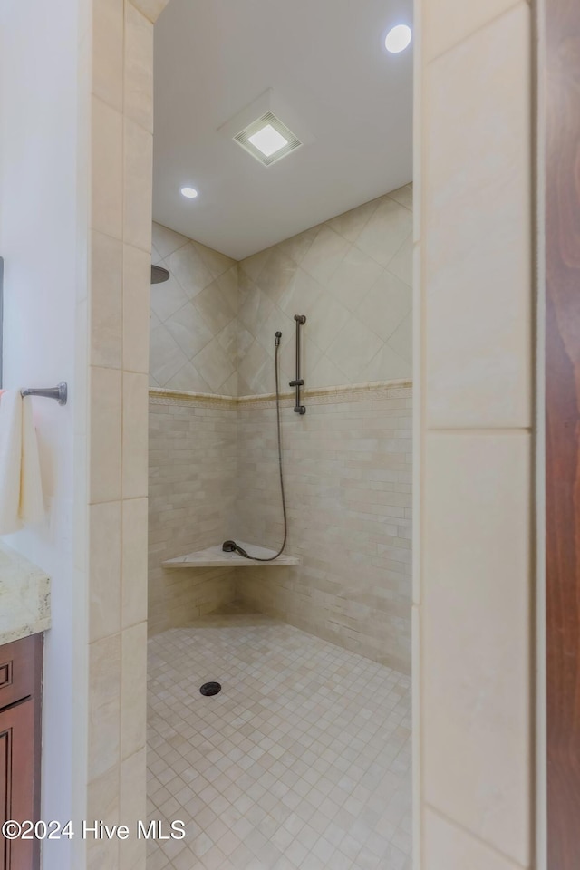 full bath with a tile shower and vanity