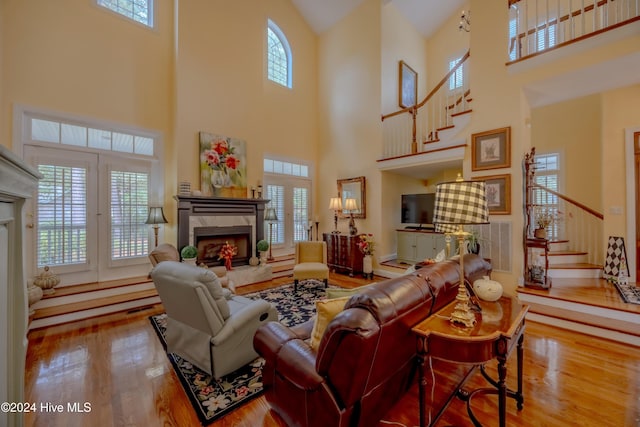 living area featuring plenty of natural light, a premium fireplace, stairway, and wood finished floors