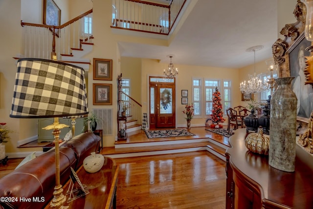 entrance foyer featuring wood finished floors, a notable chandelier, and stairs