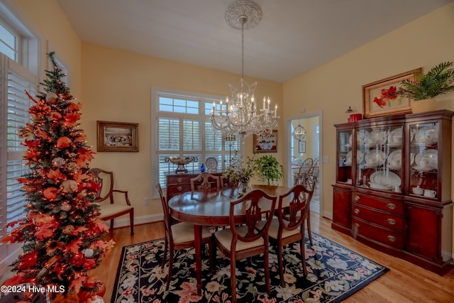 dining space with light wood-type flooring, baseboards, and a chandelier