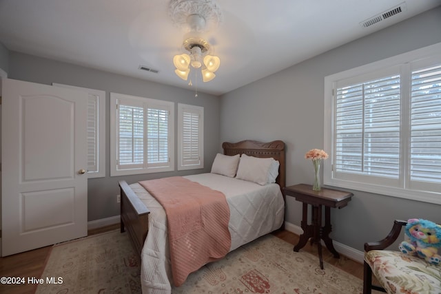 bedroom with visible vents, baseboards, and wood finished floors