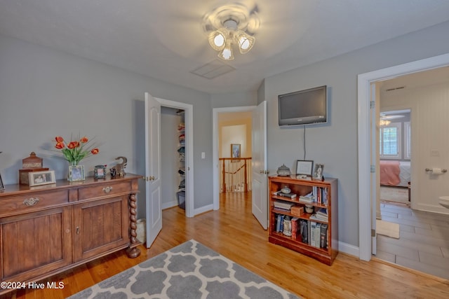 living area featuring light wood-type flooring, baseboards, ceiling fan, and an upstairs landing