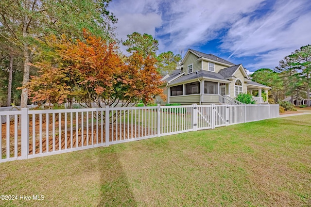 view of front of home with a front yard, a sunroom, a gate, and fence private yard