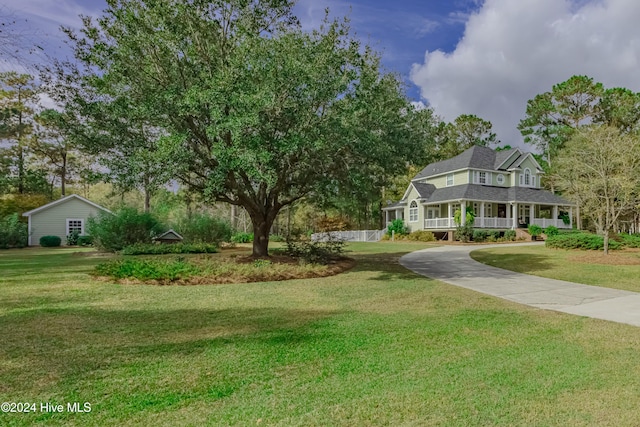 view of front of home featuring a porch, concrete driveway, and a front yard