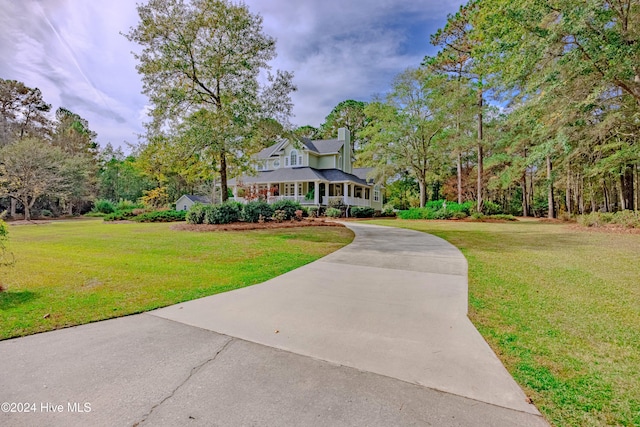 view of front of home with driveway, a chimney, and a front yard