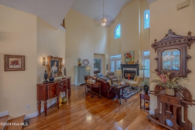 living room with light wood-type flooring, a warm lit fireplace, and baseboards