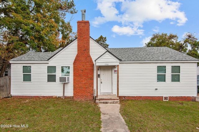 view of front facade featuring cooling unit, a chimney, a front yard, and a shingled roof