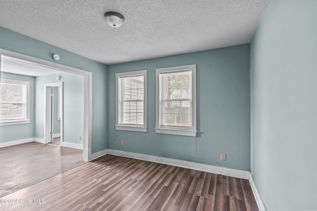 spare room featuring dark hardwood / wood-style floors and a textured ceiling